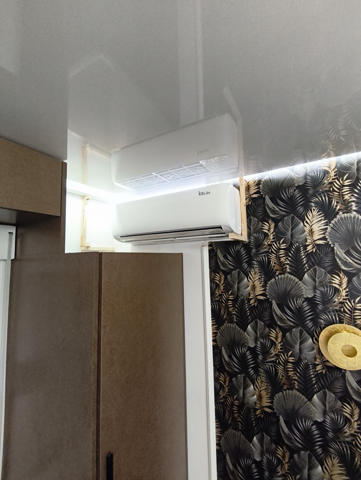AC above wardrobe in interior with tropical wallpaper